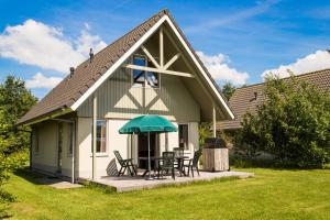a house with a table and chairs and an umbrella at RCN Vakantiepark de Potten in Offingawier