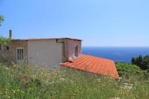 a building with an orange tile roof and the ocean at Apartments with a parking space Sveta Nedilja, Hvar - 8792 in Sveta Nedelja