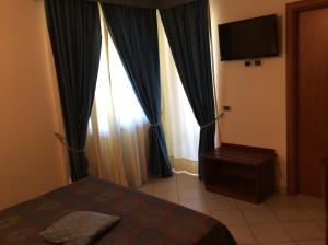 1 dormitorio con 1 cama y TV en una habitación en Cridda Hotel & Restaurant en Gizzeria