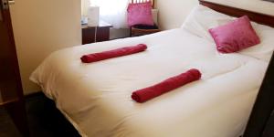 Duas meias vermelhas numa cama branca com almofadas cor-de-rosa em Bloomfield Hotel em Blackpool