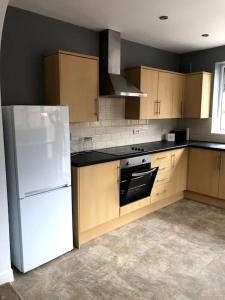 a kitchen with a white refrigerator and wooden cabinets at 2 Bedroom Bungalow in Mawdesley +11 photos