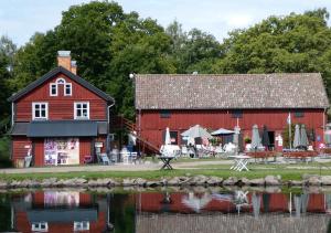 a red barn next to a body of water at Hatty's Guesthouse in Motala
