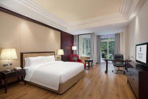 a bedroom with a large white bed and a desk at C&D Hotel,Putian in Putian