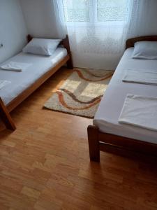 a room with two beds and a window and a rug at Hostel Dragana in Podgorica