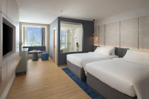 ein Hotelzimmer mit zwei Betten und einem Fernseher in der Unterkunft Miracle Grand Convention Hotel in Bangkok