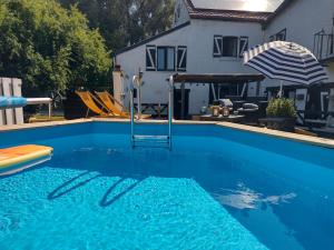 a blue swimming pool with an umbrella and a house at Moulin De Moxhe micro gîte et gîte - Bed & Dreams in Moxhe
