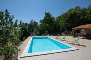 a swimming pool in a yard with chairs and trees at Villa Kruno, with the pool and spectacular sea view in Opatija