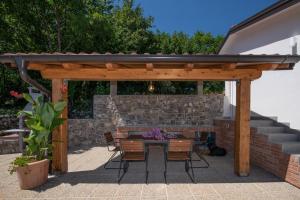 un patio con pergolato in legno, tavolo e sedie. di Villa Kruno, with the pool and spectacular sea view a Opatija
