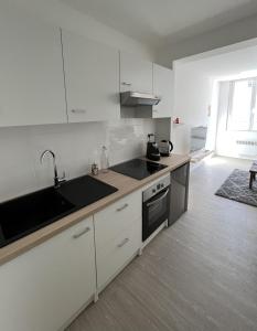 eine weiße Küche mit einer Spüle und einem Herd in der Unterkunft Appartement situé en plein coeur du centre-ville in Rochefort