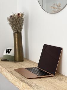 einen Laptop auf einem Holztisch mit einer Blumenvase in der Unterkunft Appartement situé en plein coeur du centre-ville in Rochefort