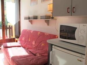 a living room with a red couch and a microwave at Appartement Vars, 2 pièces, 4 personnes - FR-1-330B-69 in Vars