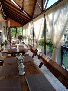 a dining room with wooden tables and white curtains at Neon2 - Vendégház in Orosháza