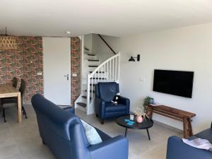 a living room with two blue chairs and a tv at Appartement 5 in Vrouwenpolder