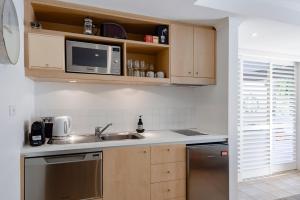 eine Küche mit einer Spüle und einer Mikrowelle in der Unterkunft Oceans Eleven at Iluka Resort Apartments in Palm Beach