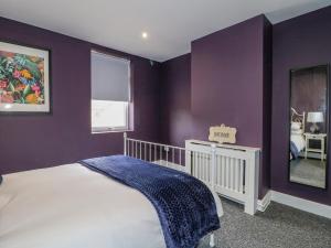 a bedroom with purple walls with a bed and a mirror at Riverside Cottage in Belper