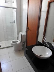 a bathroom with a white toilet and a sink at Apartamento excelente e espaçoso no Iloa Residence in Barra de São Miguel