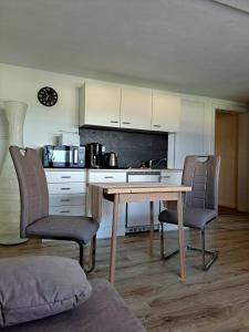 a kitchen with a wooden table and two chairs at Ferienapartment-Barbara in Langscheid