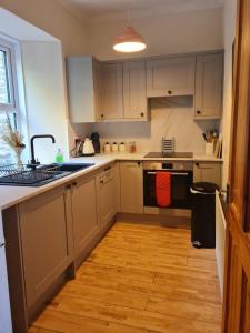 a kitchen with white cabinets and a wooden floor at Fisherman Cottage in Wick