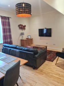 a living room with a black leather couch and a tv at Fisherman Cottage in Wick