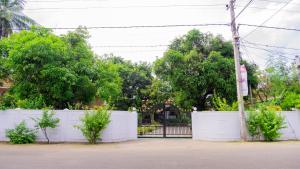 a white fence with trees in front of a house at Flamingo Villa in Jaffna