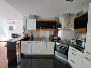 cocina con armarios blancos y encimera negra en Apartamento Vila Rosa - PRAIA DA ROCHA, en Portimão