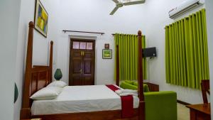 a bedroom with a bed and a green chair at Flamingo Villa in Jaffna