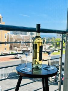 a bottle of wine and two wine glasses on a table at Caline Vip Apartments, beach close in Bloubergstrand