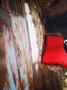 a red couch sitting next to a rusty door at La Cueva Refugio in Las Palmas de Gran Canaria +21 photos