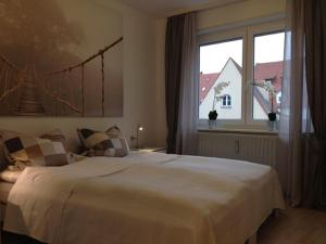 a bedroom with a large white bed and a window at Steinhauser`s Ferienwohnungen in Augsburg
