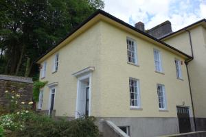 a yellow house with white windows and a wall at The East Wing in Glasbury