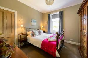 1 dormitorio con 1 cama con manta roja y ventana en 3 Castle Terrace, en Crail