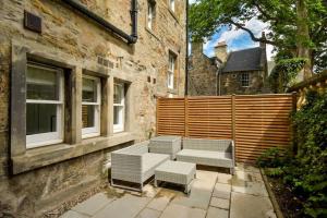 un patio con 2 bancos junto a un edificio en 14 South Street, en St Andrews