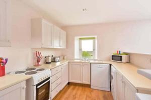 a white kitchen with white appliances and a window at Meggie Allans in Crail