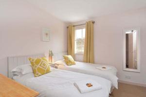 Kittocks Den في سانت أندروز: غرفة نوم بسريرين مع وسائد صفراء وبيضاء