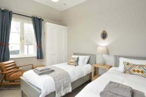 a bedroom with two beds and a chair and a window at Steprock Cottage in St. Andrews