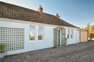 a white house with a garage at Mick's Cottage in Crail