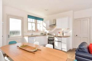a kitchen and dining room with a wooden table at Mick's Cottage in Crail