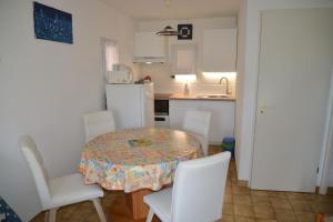 een keuken met een tafel en witte stoelen en een keuken met een wastafel bij Appartement 2 pièces RDC jardin dans résidence avec piscine in Arzon