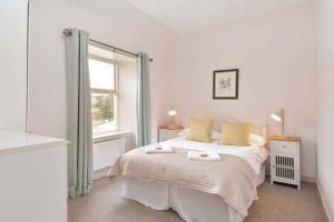 a white bedroom with a bed and a window at Kittocks Cottage in St. Andrews