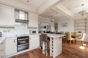 a kitchen with white cabinets and a table with chairs at 30 Lade Braes in St. Andrews