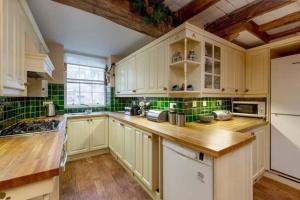 una cucina con armadi bianchi e piastrelle verdi di 19 Shoregate a Crail