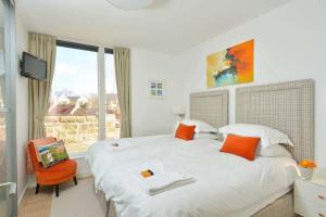 a bedroom with a large white bed with an orange chair at The Golf Flat, Westburn Lane in St. Andrews
