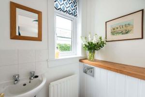 une salle de bain avec un lavabo et un vase de fleurs dans l'établissement Willow Cottage, North Street, à St Andrews 20 autres photos