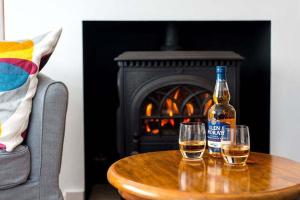 - une bouteille et deux verres sur une table avec une cheminée dans l'établissement Willow Cottage, North Street, à St Andrews
