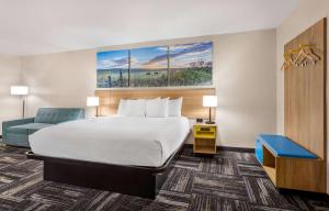 a hotel room with a bed and a blue chair at Days Inn by Wyndham Paris in Paris