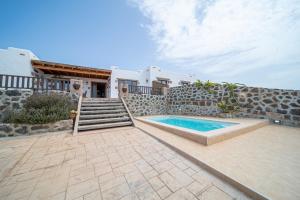 a house with a swimming pool and a stone wall at Villa Alisios La Asomada in Tías