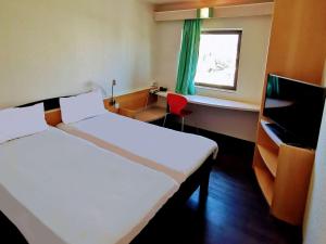 a hotel room with two beds and a window at Hotel ibis Leiria Fatima in Leiria