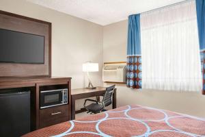 a hotel room with a bed and a desk with a television at Super 8 by Wyndham Lenexa Overland Park Area/Mall Area in Lenexa