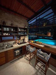 uma cozinha com uma piscina e duas cadeiras em Cobertura Duplex com piscina e Suítes Barão Vermelho em Morro de São Paulo