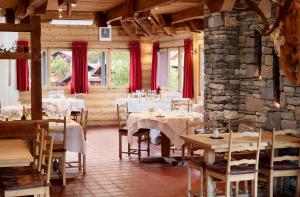 un comedor con mesas, sillas y cortinas rojas en Hotel Mont Rouge, en Nendaz